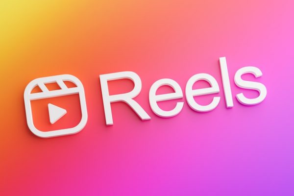 imagem em degrade rosa com o símbolo do reels e escrito com letra 3D a palavra "reels"
